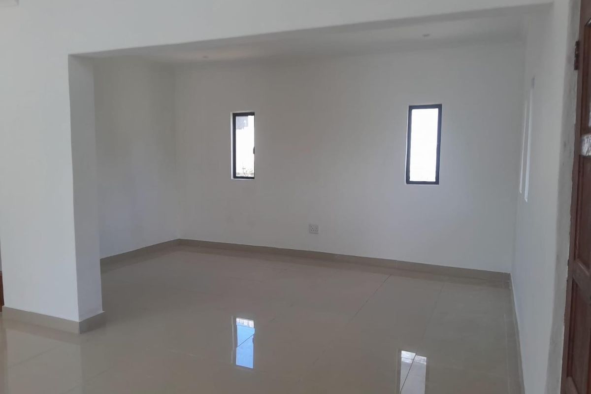 A bright, empty living area featuring neutral tiled flooring and clean white walls, offering a versatile blank canvas for interior design.