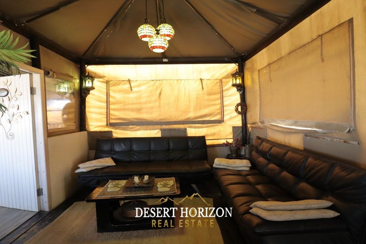 A rustic, tented living area featuring a canvas structure, integrated lighting, and a cozy lounge space suitable for relaxed guest house accommodation.