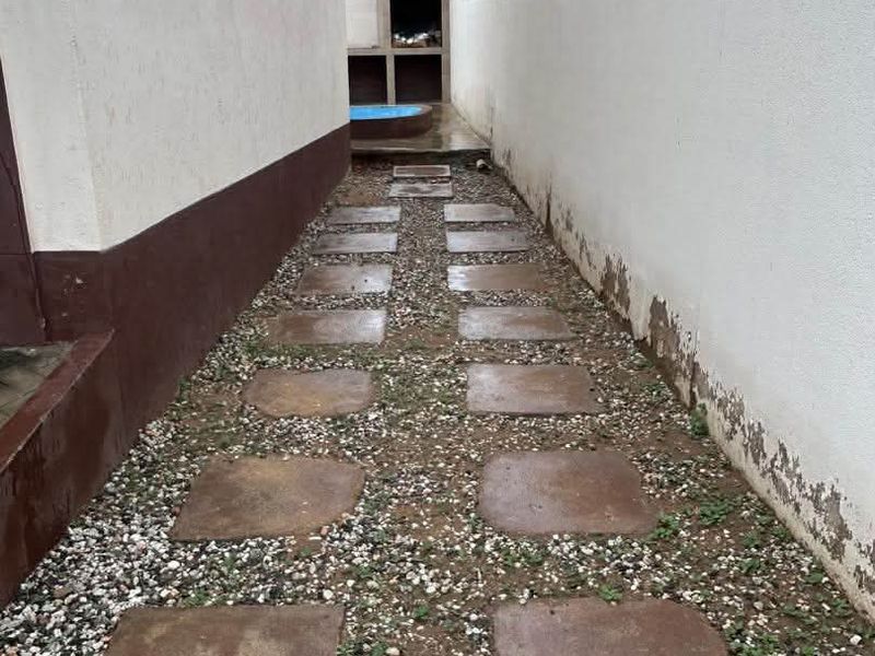 Side passage leading to a rear outdoor area featuring a built-in braai, paved walkway, and high boundary walls with security razor wire.