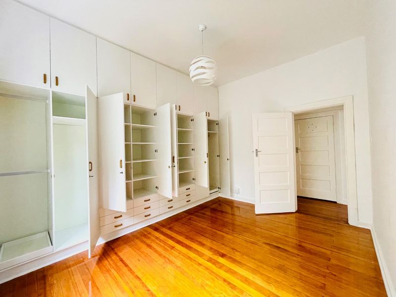 Spacious bedroom featuring polished hardwood flooring and extensive built-in floor-to-ceiling cabinetry providing ample storage space.