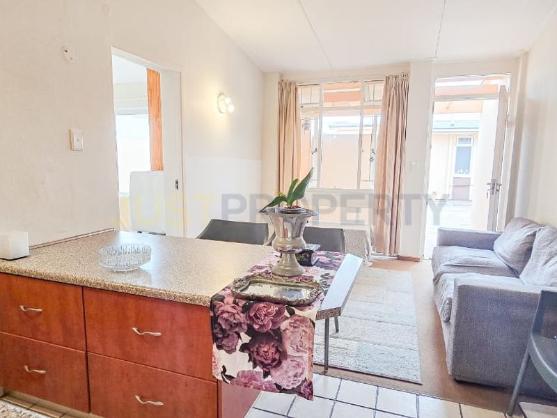 Open-plan living and kitchen area featuring granite countertops, tiled flooring, and direct access to an outdoor patio space.