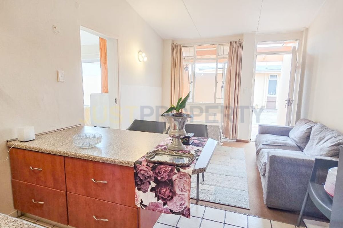 Open-plan living and kitchen area featuring granite countertops, tiled flooring, and direct access to an outdoor patio space.