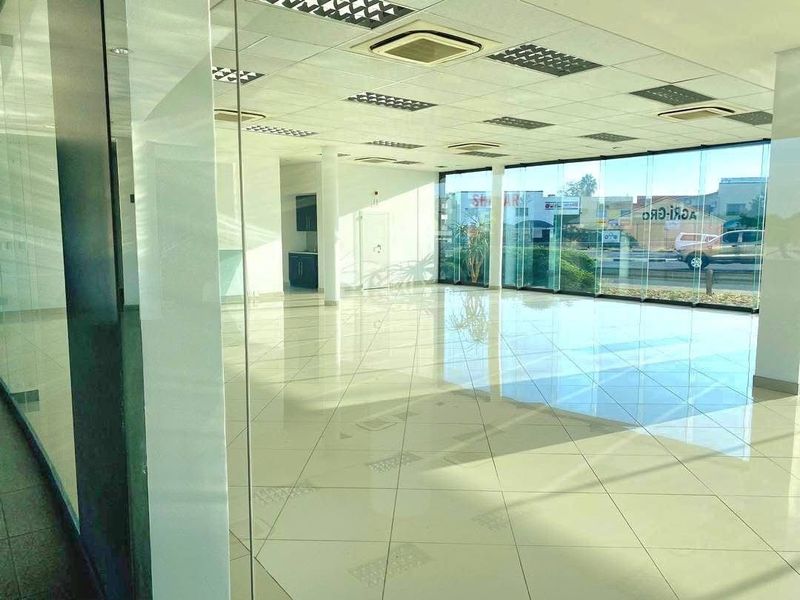 Spacious open-plan retail area featuring polished tiled floors, extensive glass frontage for natural light, and integrated ceiling-mounted air conditioning.