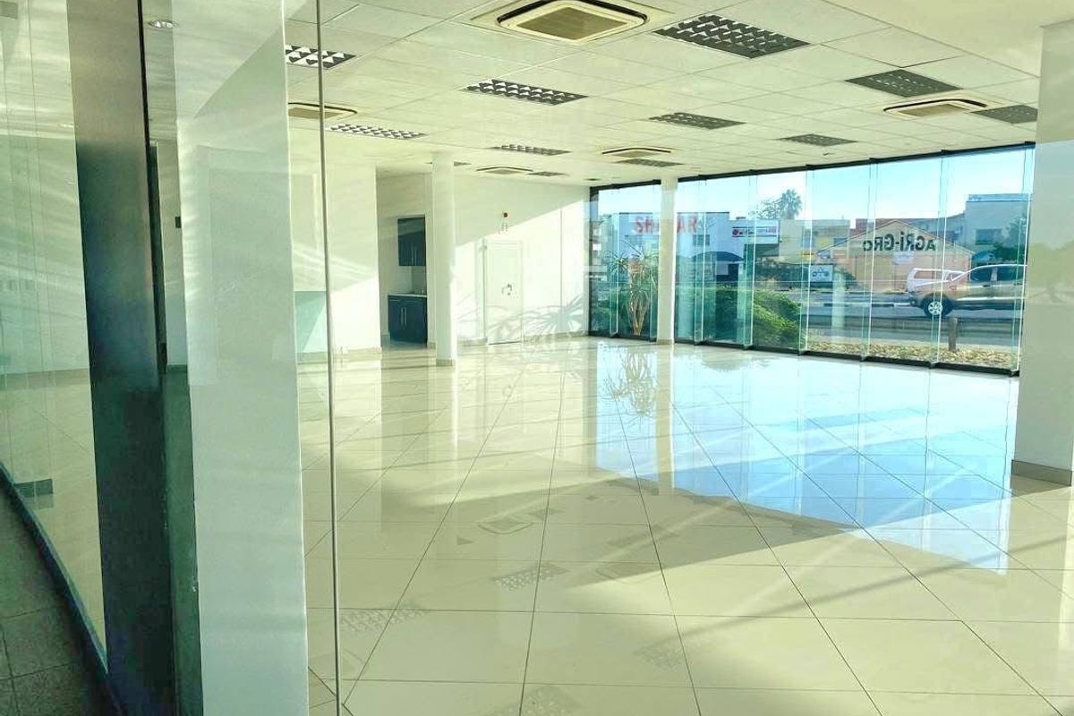 Spacious open-plan retail area featuring polished tiled floors, extensive glass frontage for natural light, and integrated ceiling-mounted air conditioning.