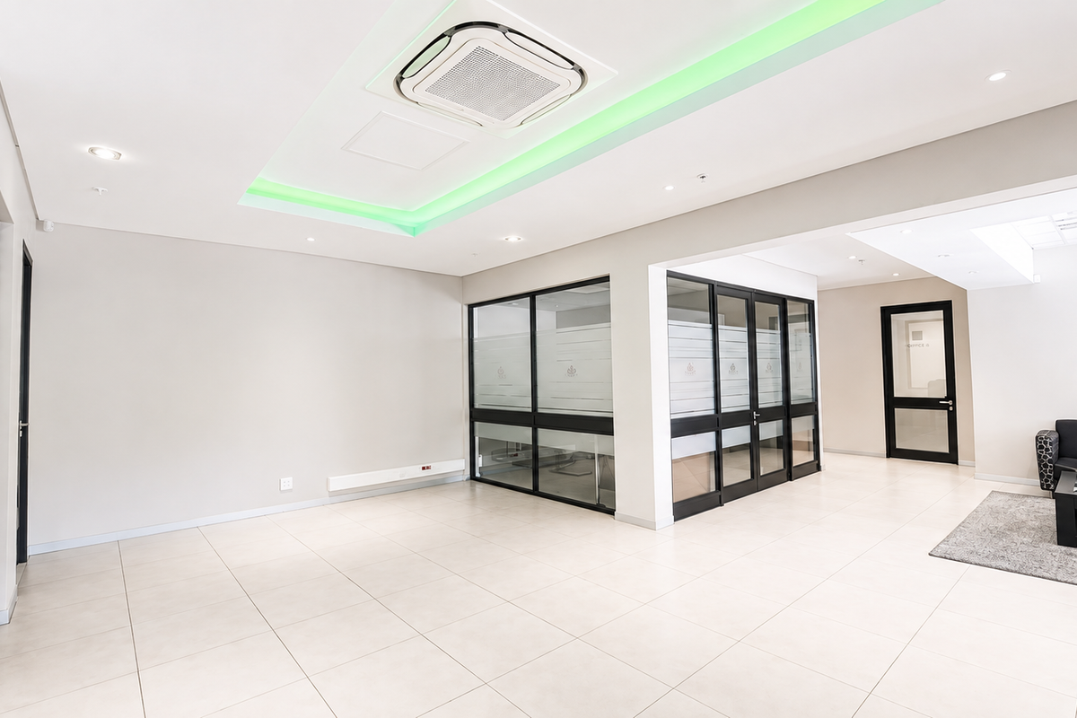 Modern open-plan office space featuring tiled flooring, glass partitions, and integrated ceiling lighting with ducted air conditioning.