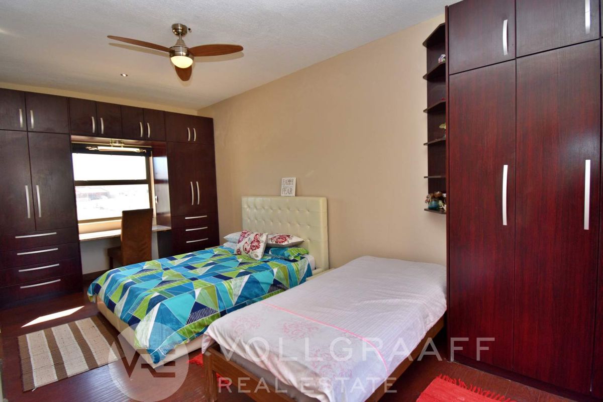 Spacious bedroom featuring extensive built-in dark wood cabinetry, integrated desk space, and a ceiling fan.
