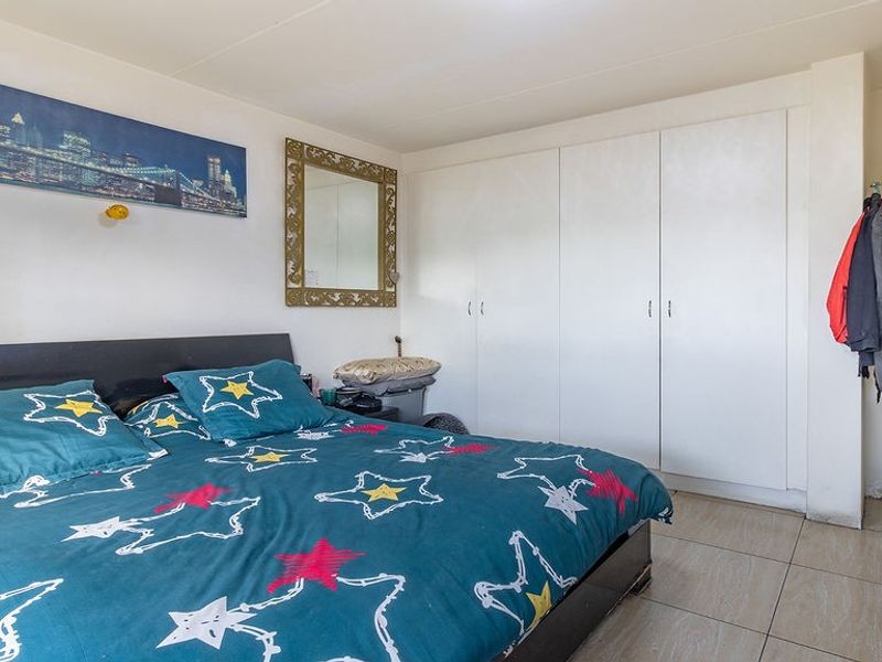 A bedroom featuring tiled flooring and ample built-in cupboard storage space.