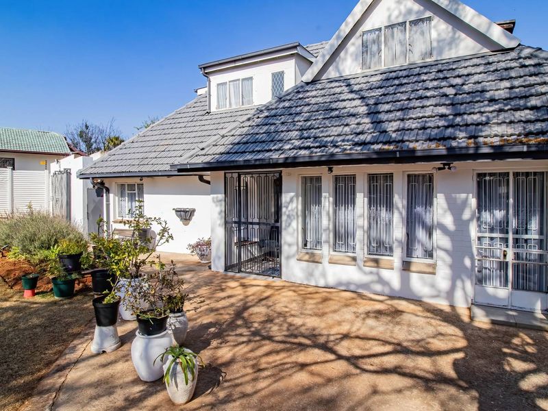 Rear view of the property featuring a paved patio area, security gates, and a tiled roof structure.