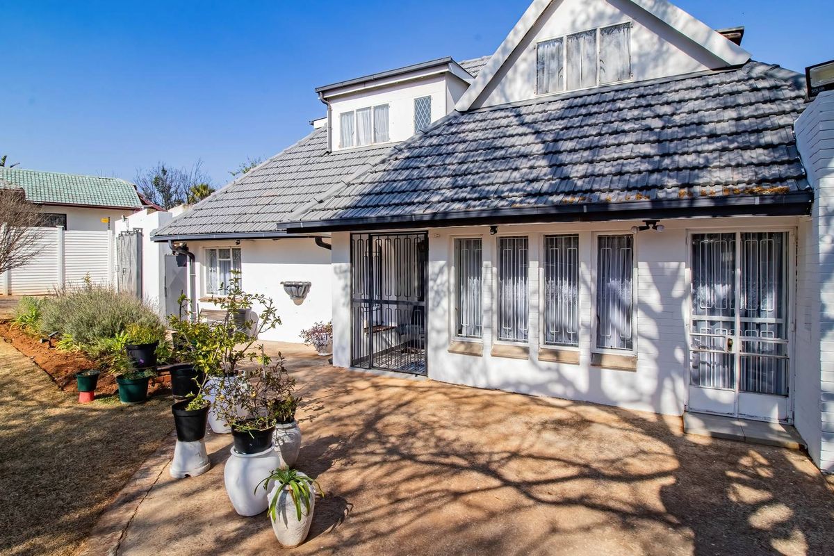 Rear view of the property featuring a paved patio area, security gates, and a tiled roof structure.
