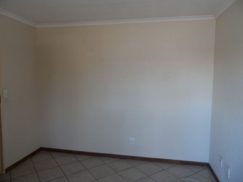 An empty bedroom featuring tiled flooring, neutral walls, and standard electrical fixtures, providing a blank canvas for personalization.
