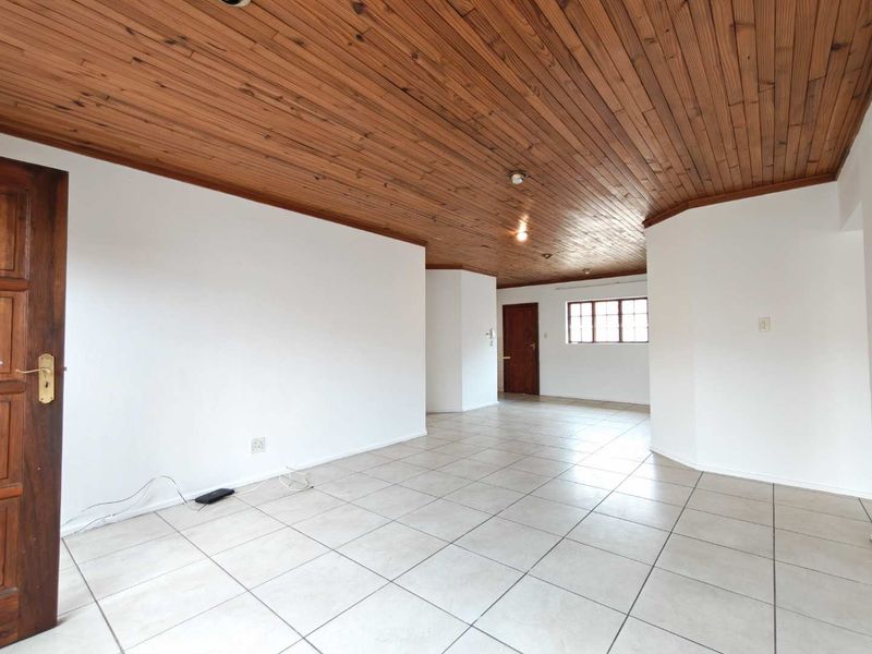 Spacious living area featuring ceramic floor tiles and a distinctive wooden tongue and groove ceiling, offering a neutral canvas for interior design.