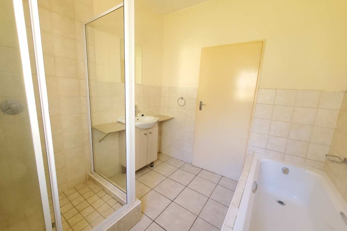 A functional bathroom featuring a separate shower enclosure, a built-in bathtub, and a vanity basin with tiled flooring and wall finishes.