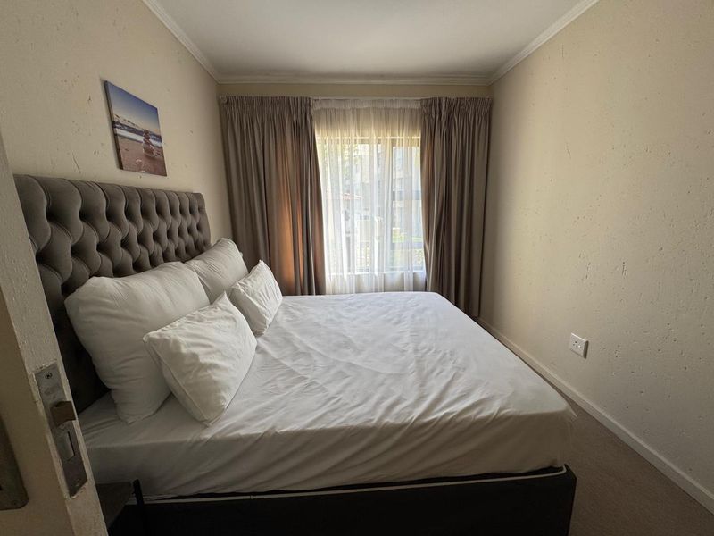 A bedroom featuring textured walls, neutral curtains, and standard electrical fixtures. The space requires minor cosmetic attention to wall finishes.