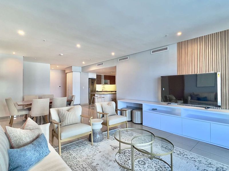 Spacious open-plan living and dining area featuring modern tiled floors, recessed lighting, ducted air conditioning, and a stylish timber slat feature wall.