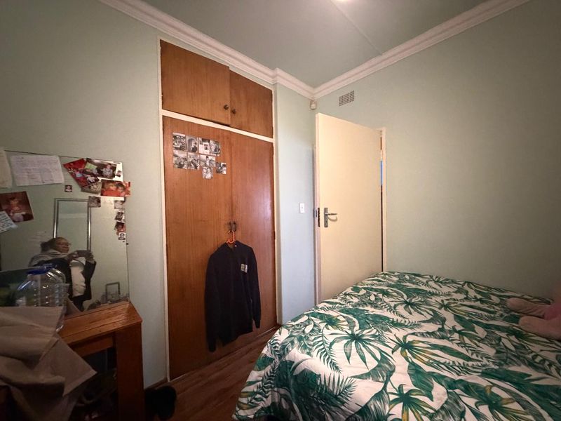 A bedroom featuring built-in wooden cupboards, crown molding, and laminate flooring.