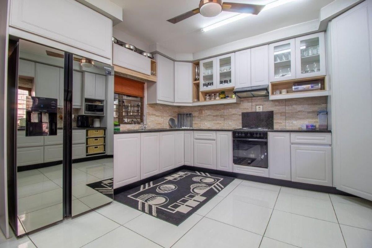 Modern kitchen featuring white cabinetry, stone tile backsplash, integrated oven with extractor fan, and tiled flooring.