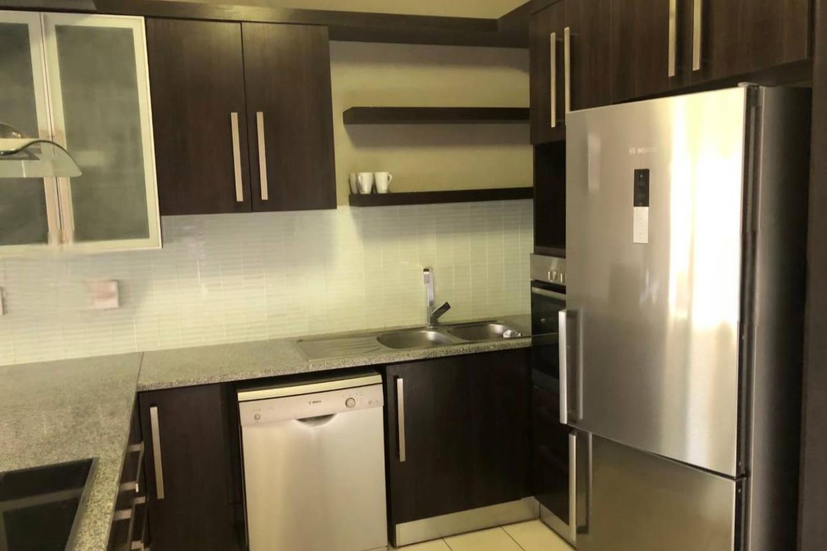 Modern kitchen featuring dark wood cabinetry, granite countertops, tiled backsplash, and integrated stainless steel appliances including a dishwasher and oven.