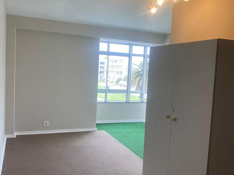 A bedroom featuring carpeted flooring, a large multi-pane window, and a ceiling-mounted spotlight fixture.