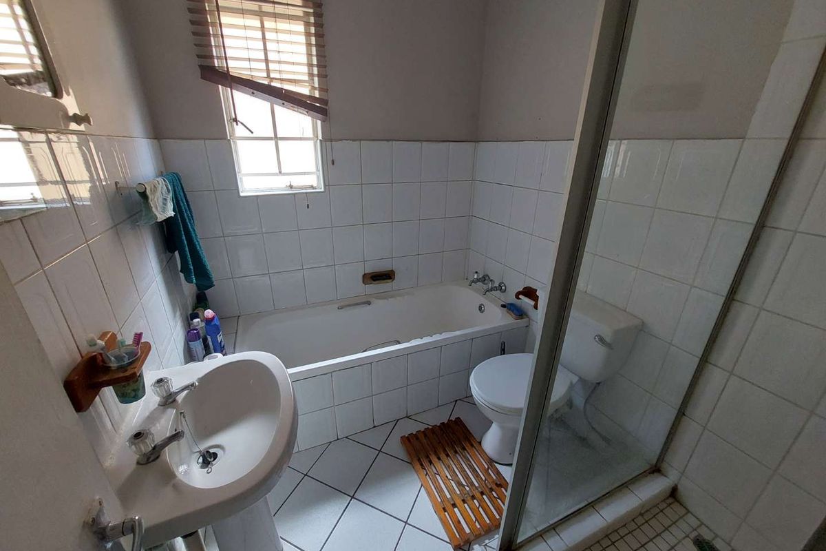 A functional bathroom featuring a pedestal basin, a bathtub with tiled surround, and a separate glass-enclosed shower cubicle.