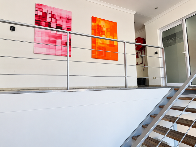 Modern office entrance featuring a timber staircase with stainless steel balustrades and glass-partitioned office doors.