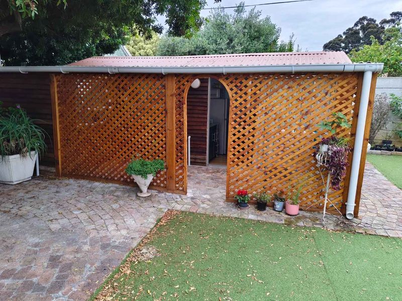A covered outdoor patio area featuring timber lattice screening, corrugated roofing, and paved flooring, providing a sheltered transition space to the interior.