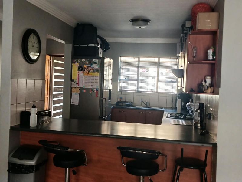 Functional kitchen featuring a breakfast bar, laminate cabinetry, tiled backsplash, and a built-in hob, offering a practical layout for daily meal preparation.