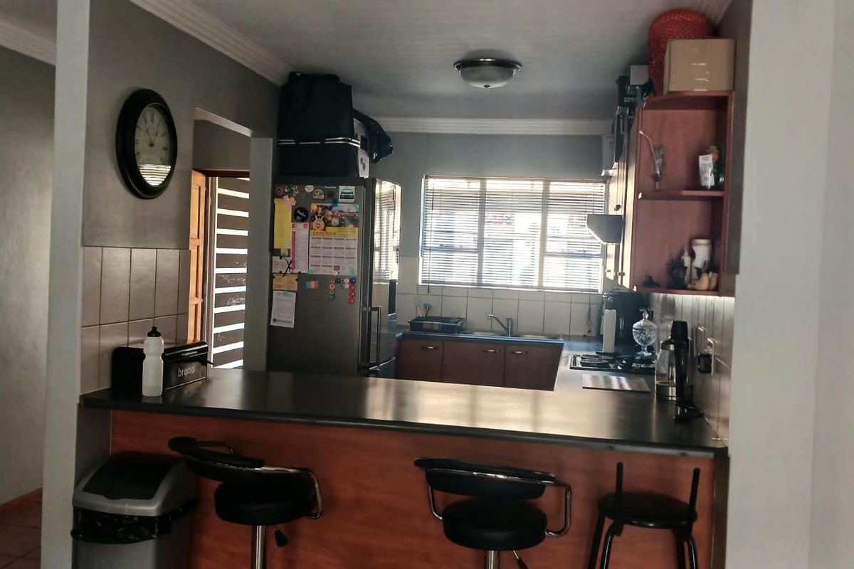 Functional kitchen featuring a breakfast bar, laminate cabinetry, tiled backsplash, and a built-in hob, offering a practical layout for daily meal preparation.