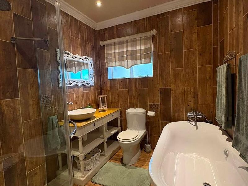A well-appointed bathroom featuring wood-look wall tiling, a freestanding bathtub, a separate glass-enclosed shower, and a vanity with a vessel sink.