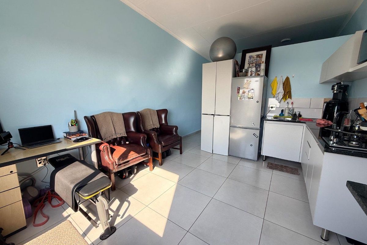 Open-plan living area featuring tiled flooring and a functional kitchen with built-in cabinetry, granite countertops, and a gas hob.