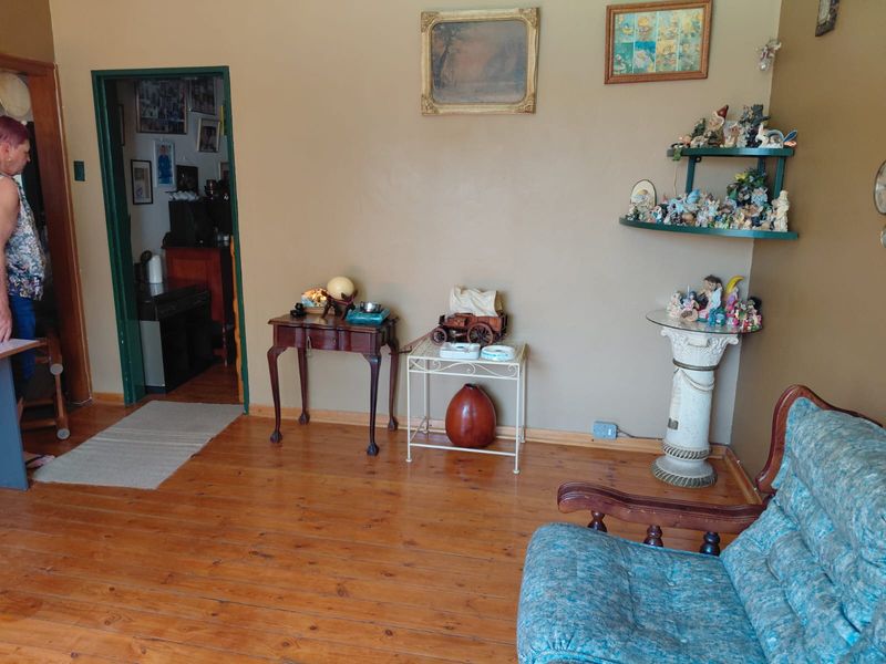 A living room area featuring polished timber flooring and a doorway leading to an adjacent space.