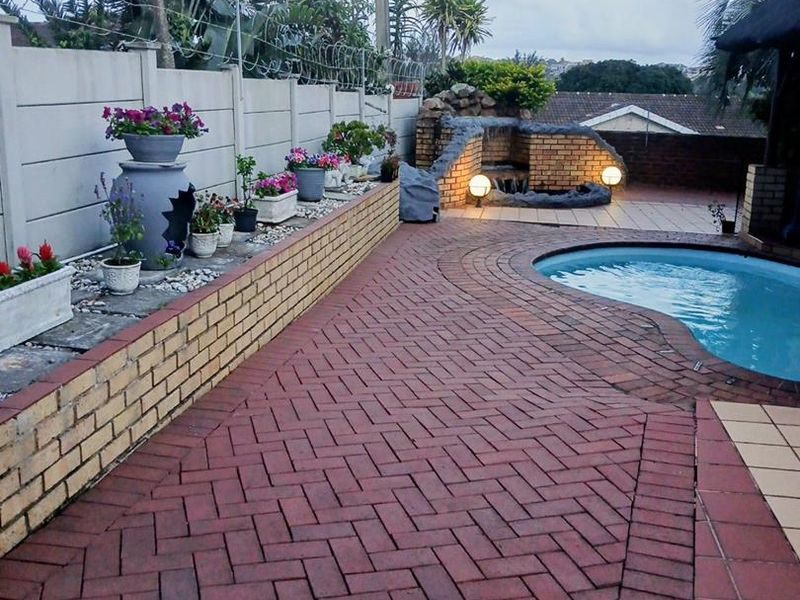 Outdoor pool area featuring brick paving, a built-in water feature, and a secure perimeter wall with razor wire.