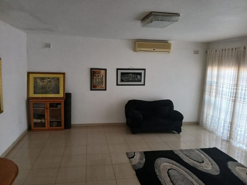 A living room featuring tiled flooring, a wall-mounted air conditioning unit, and sliding glass doors leading to an outdoor area.