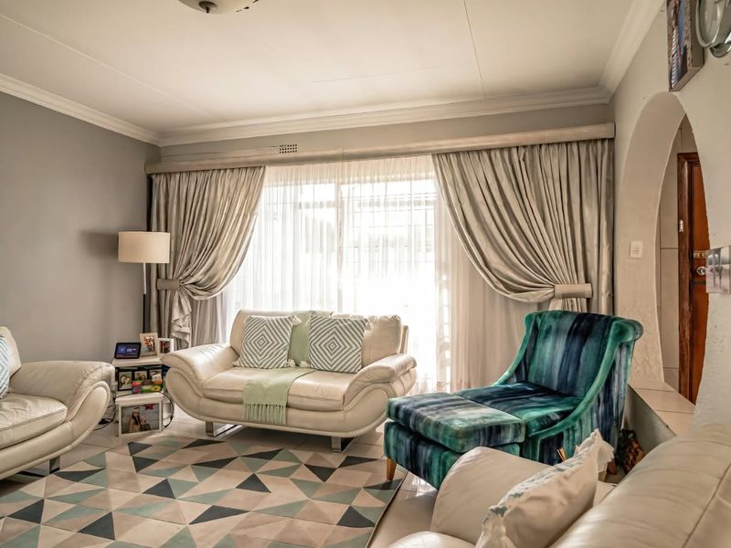 A comfortable living room featuring a large sliding glass door, decorative archway, and classic cove cornice detailing.