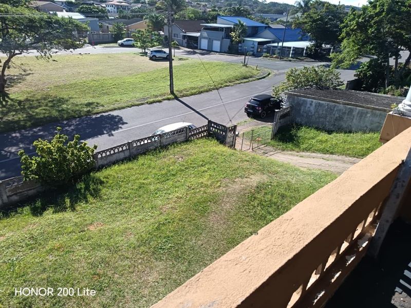 Elevated view overlooking the front garden, boundary wall, and street approach of the property.