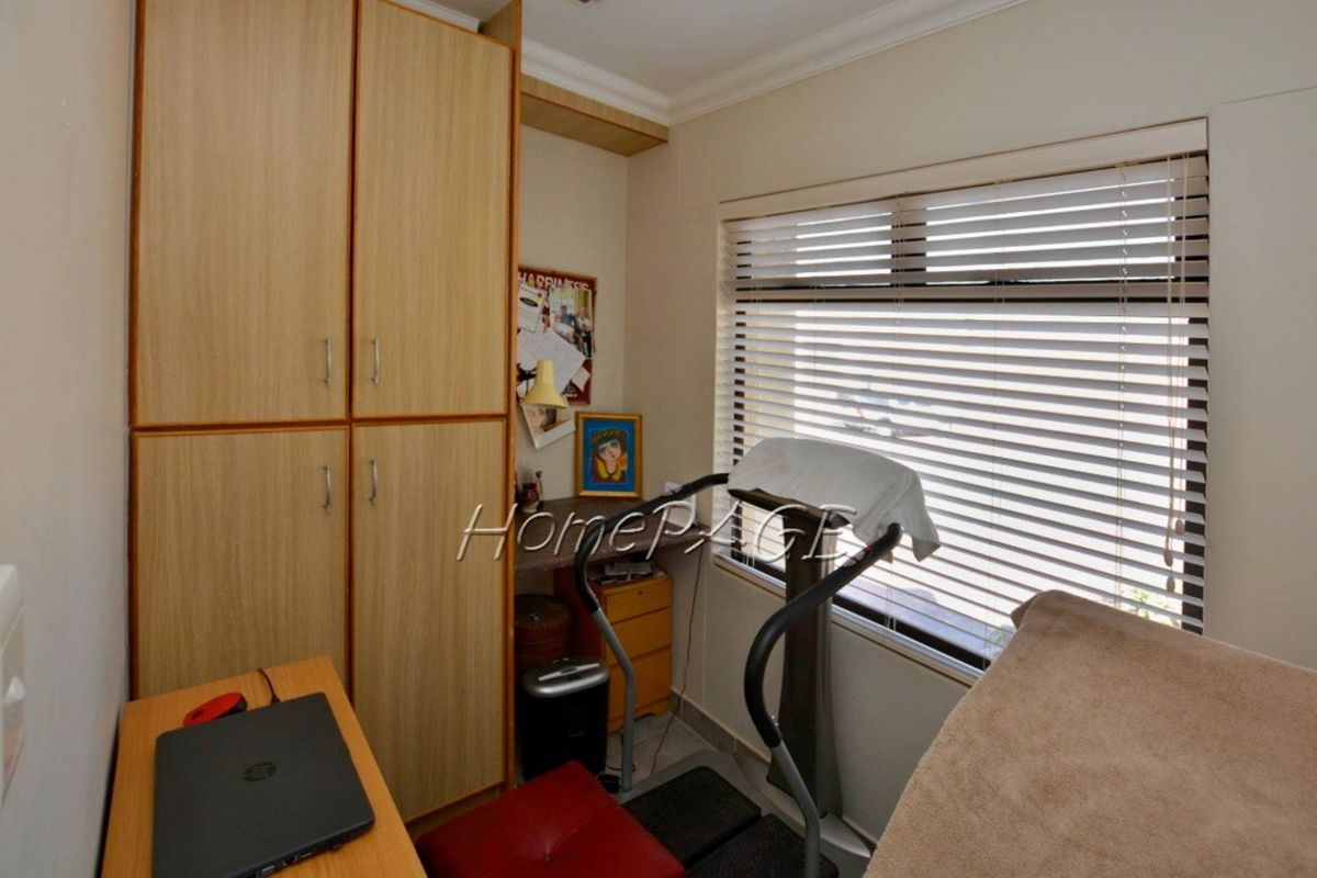 A compact bedroom or study featuring built-in wooden cabinetry and horizontal window blinds, providing functional storage and natural light.