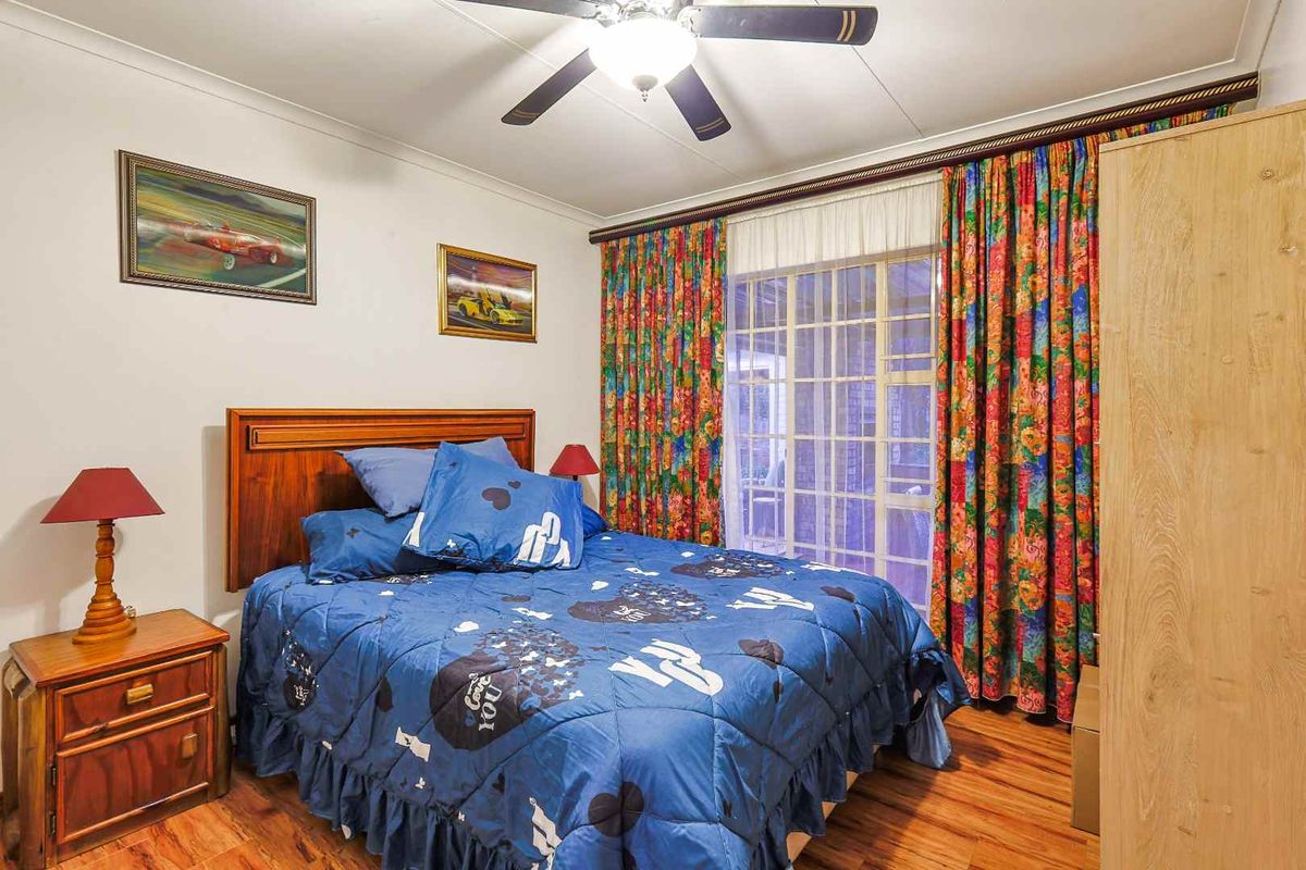 A bedroom featuring laminate flooring, a ceiling fan, and a sliding glass door providing access to the exterior.