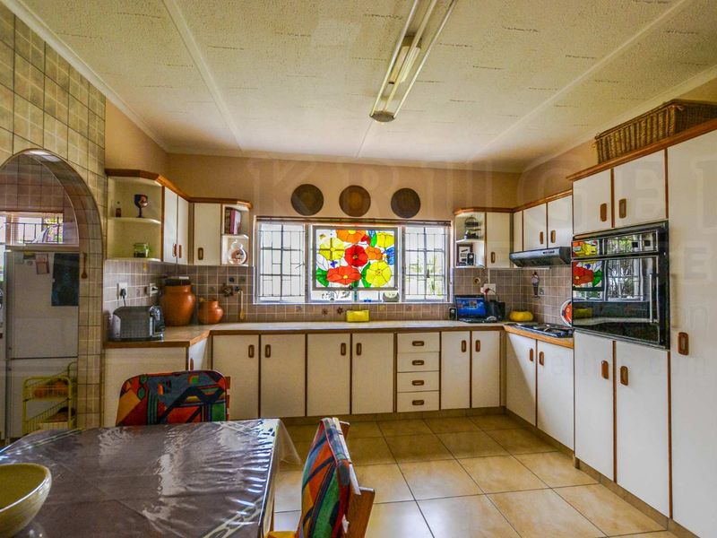 A functional kitchen featuring built-in cabinetry, tiled flooring, a built-in oven, and a decorative stained glass window feature.