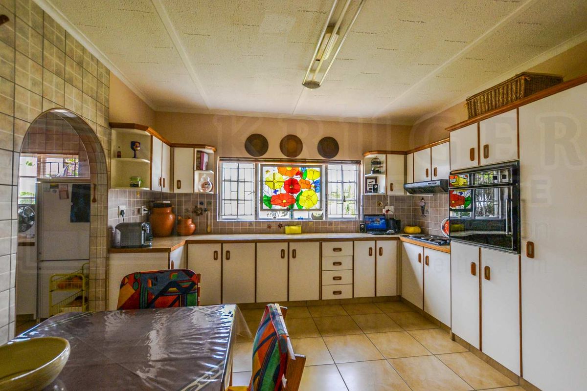 A functional kitchen featuring built-in cabinetry, tiled flooring, a built-in oven, and a decorative stained glass window feature.