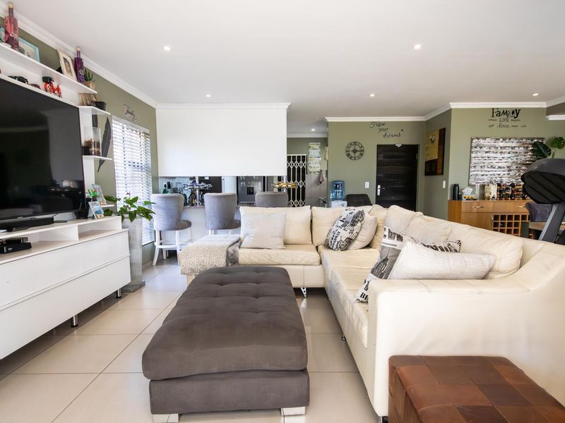 Spacious open-plan living area featuring tiled flooring, recessed lighting, and a breakfast bar connecting to the kitchen space.