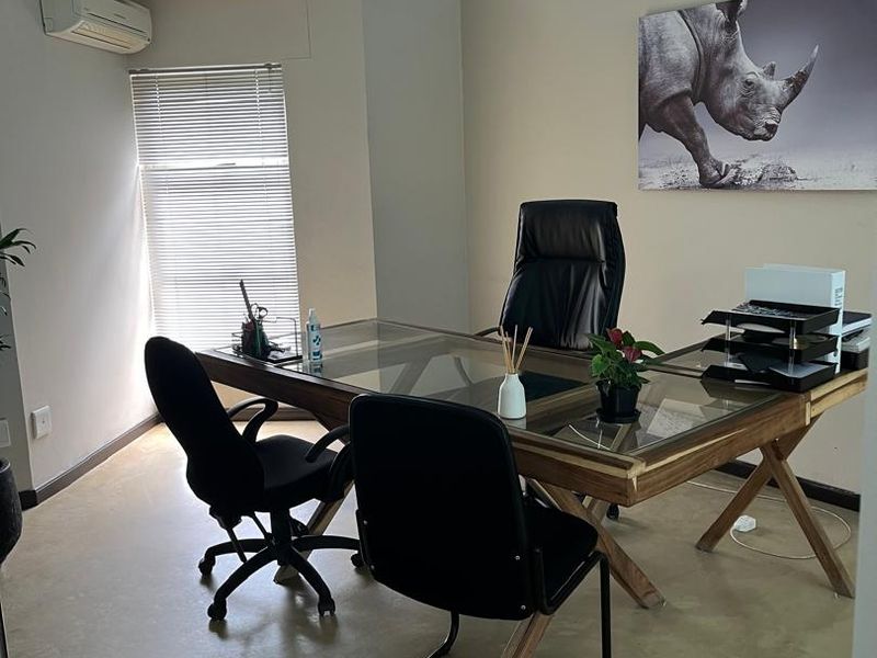 A professional office space featuring polished concrete floors, a glass partition wall, air conditioning, and natural light through venetian blinds.