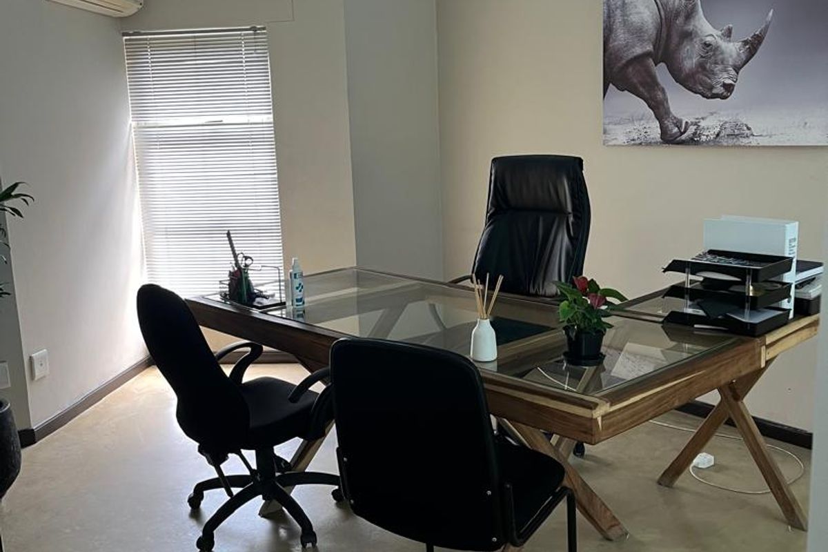 A professional office space featuring polished concrete floors, a glass partition wall, air conditioning, and natural light through venetian blinds.