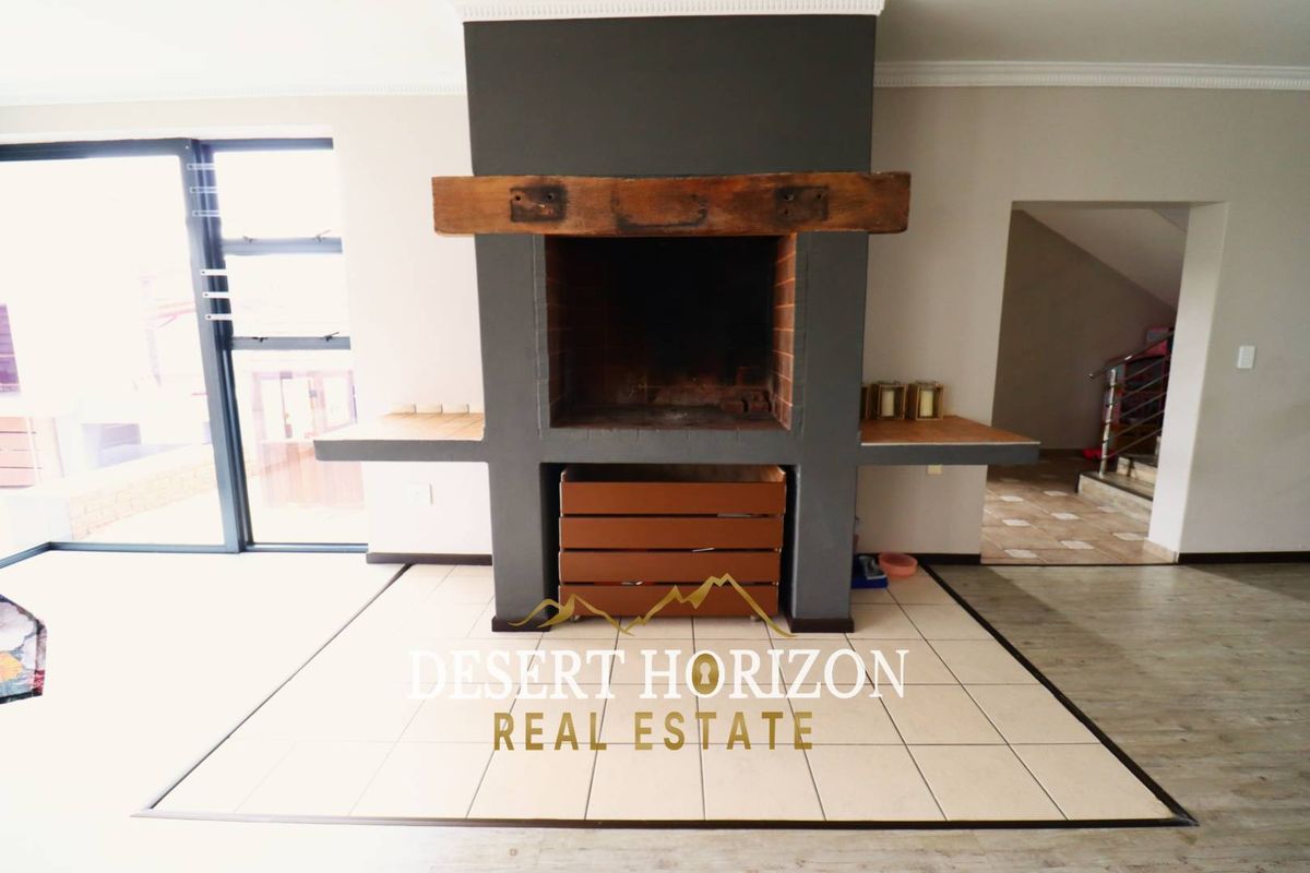 Living area featuring a prominent built-in indoor fireplace with a rustic timber mantelpiece and tiled hearth.