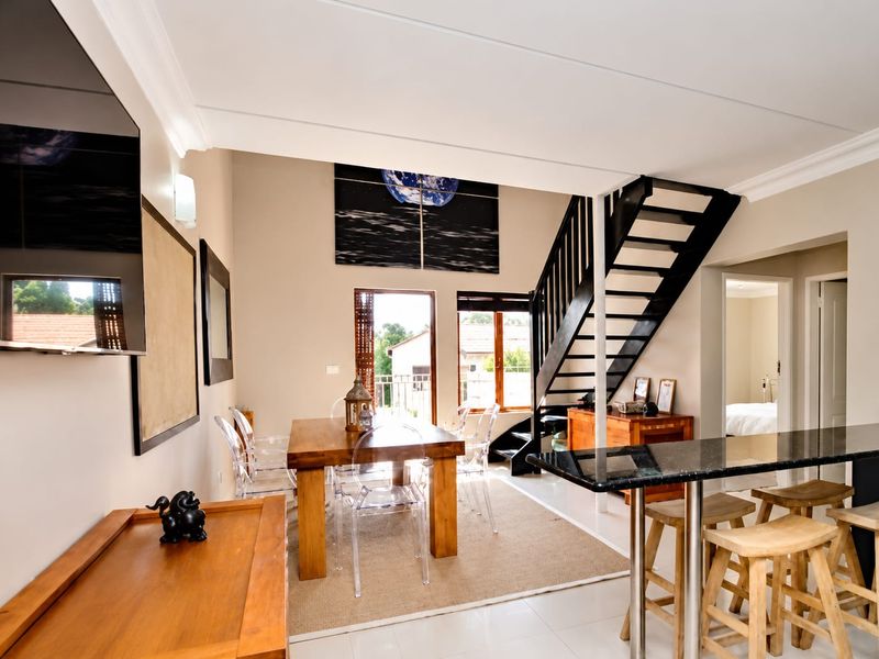 Open plan living and dining area featuring a modern staircase, breakfast bar with granite countertop, and direct access to an outdoor balcony.