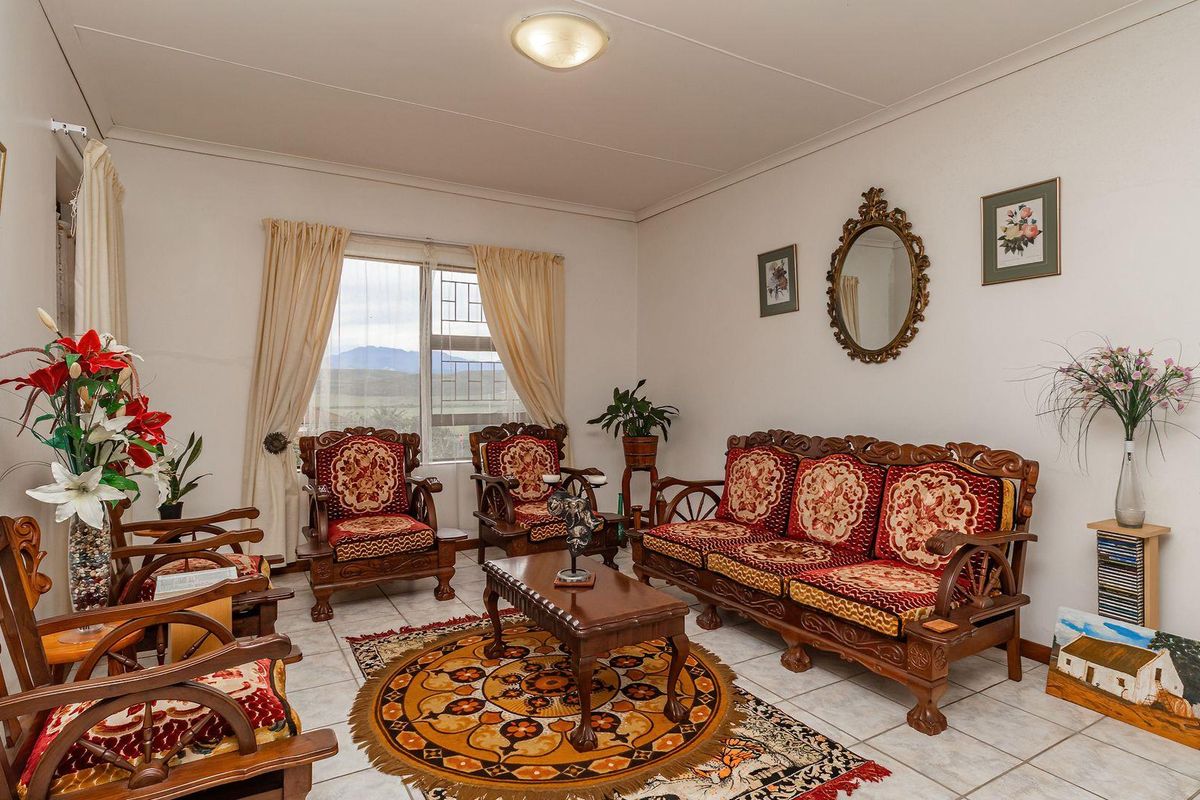 A living room featuring tiled flooring and a large window with views, providing a functional and well-lit space.