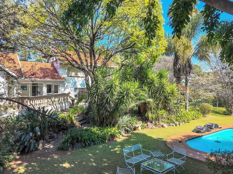 Rear view of the property featuring a swimming pool, landscaped garden, and a terrace with a classic balustrade.
