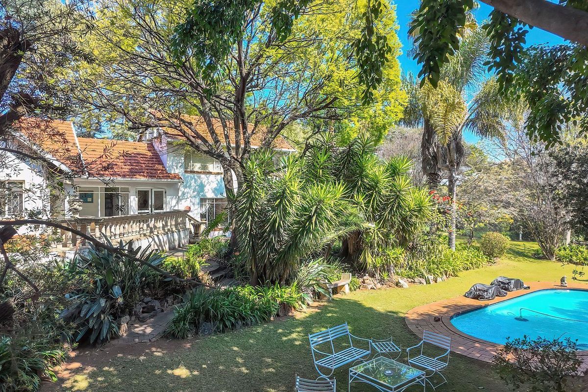 Rear view of the property featuring a swimming pool, landscaped garden, and a terrace with a classic balustrade.