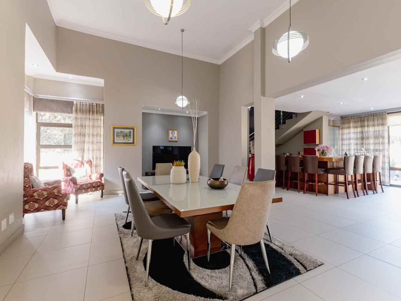 Spacious open-plan dining and living area featuring high ceilings, modern pendant lighting, tiled flooring, and a seamless transition to a built-in breakfast bar.