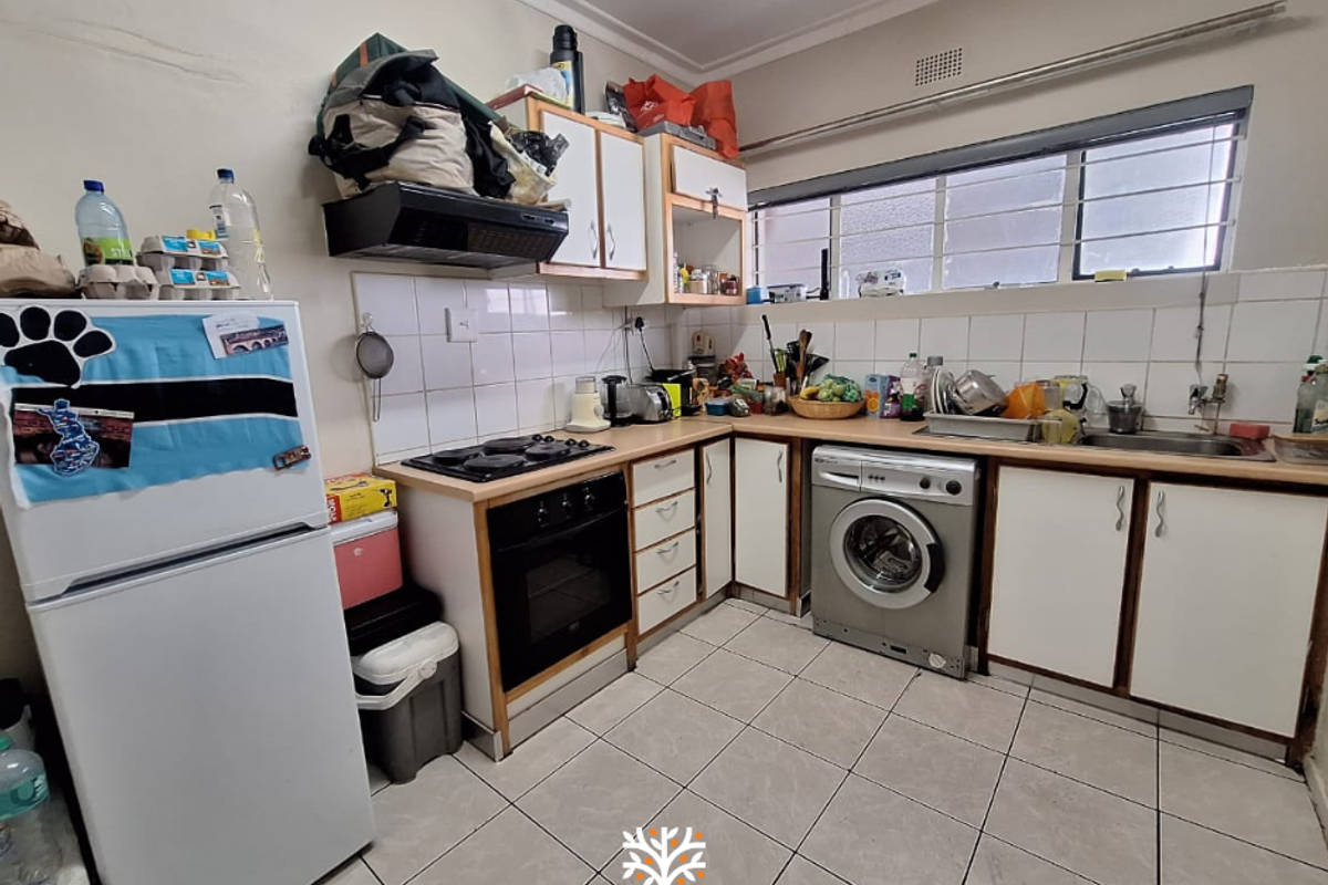 Functional kitchen featuring built-in cabinetry, integrated oven and hob, tiled flooring, and space for a washing machine under the counter.