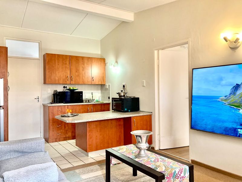 Open-plan living area featuring a functional kitchen with wood-finish cabinetry, laminate countertops, and tiled flooring, seamlessly integrated with the adjacent living space.