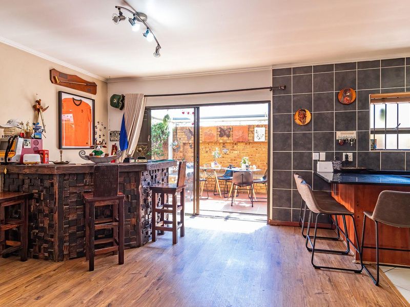Open-plan living area featuring a built-in bar, kitchen with granite countertops, and sliding glass doors leading to an outdoor patio space.
